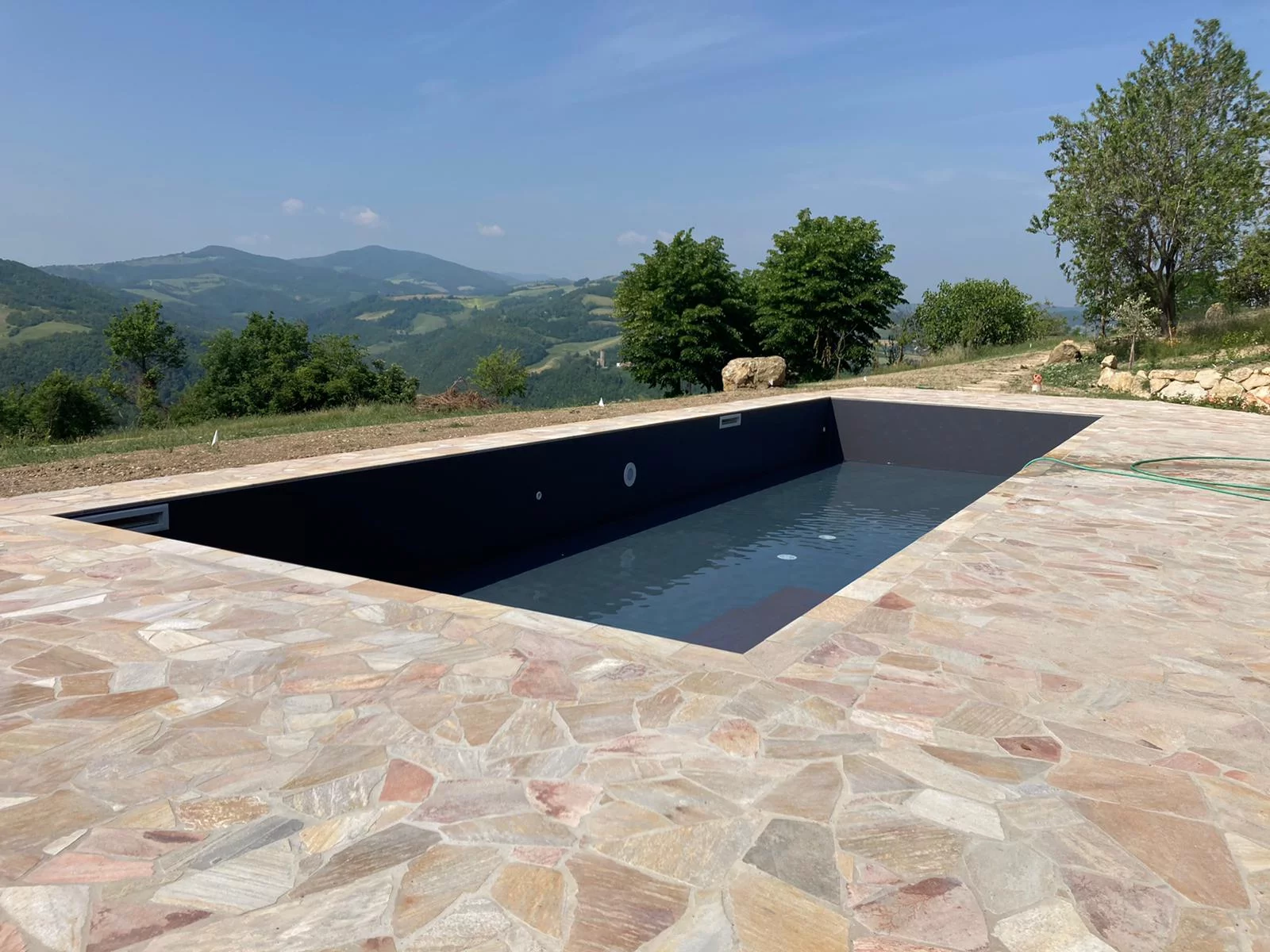 Piscina privata a skimmer, realizzata nelle colline piacentine, con rivestimento Alkorplan grigio antracite, realizzata su progetto